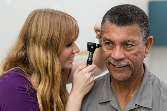 woman examines patient's ear